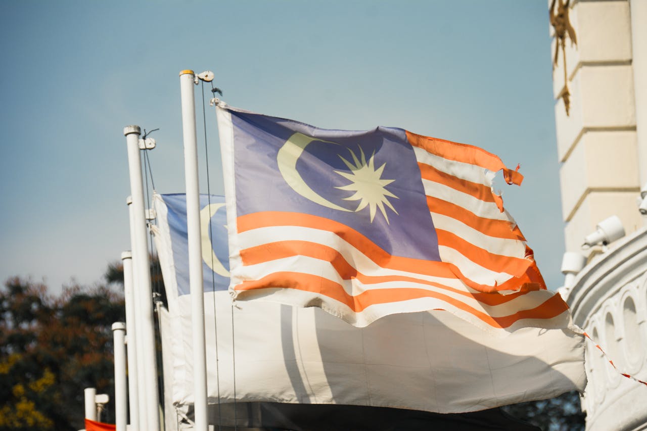 services-03 A vibrant Malaysian flag waving against a clear blue sky symbolizes national pride and patriotism.